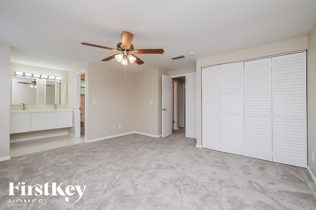 an empty living room with a ceiling fan and a closet
