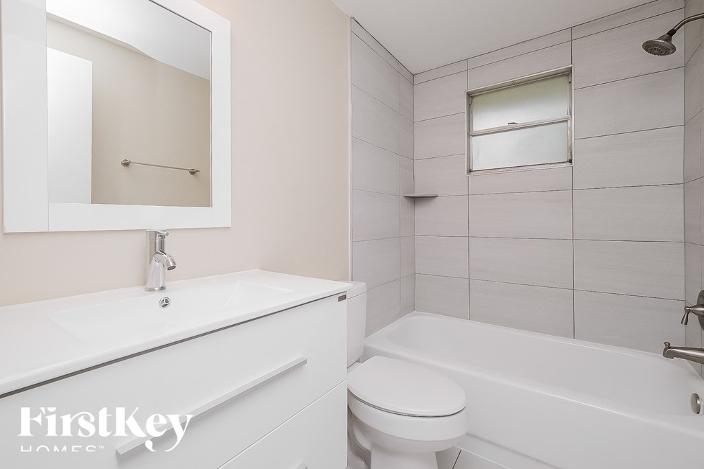 a white bathroom with a sink and toilet and a tub
