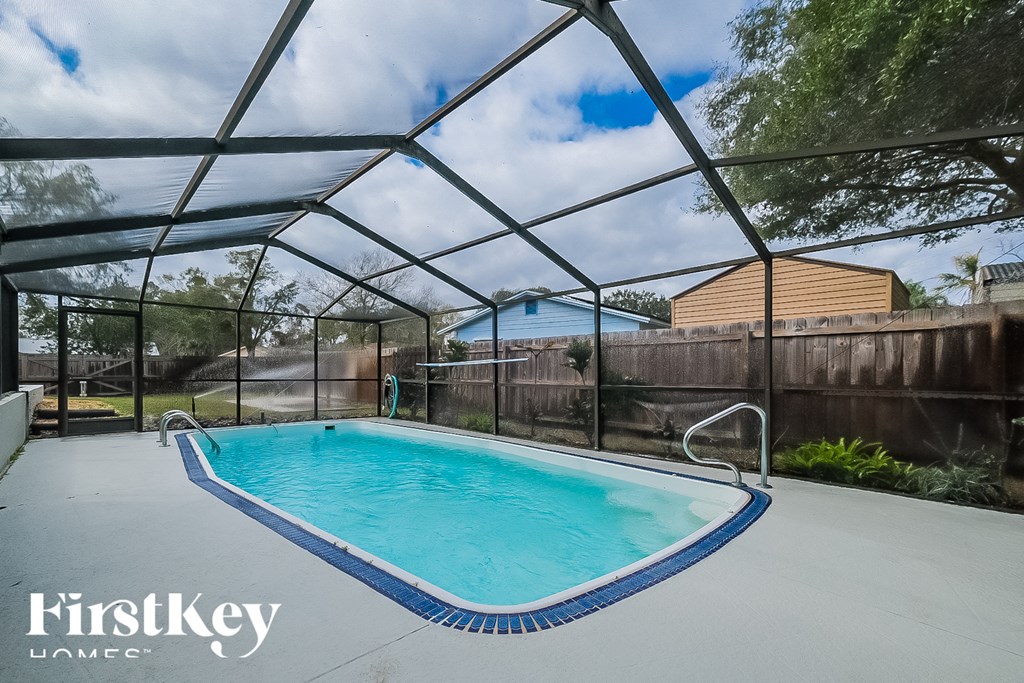 a pool in an enclosure with a fence and a house