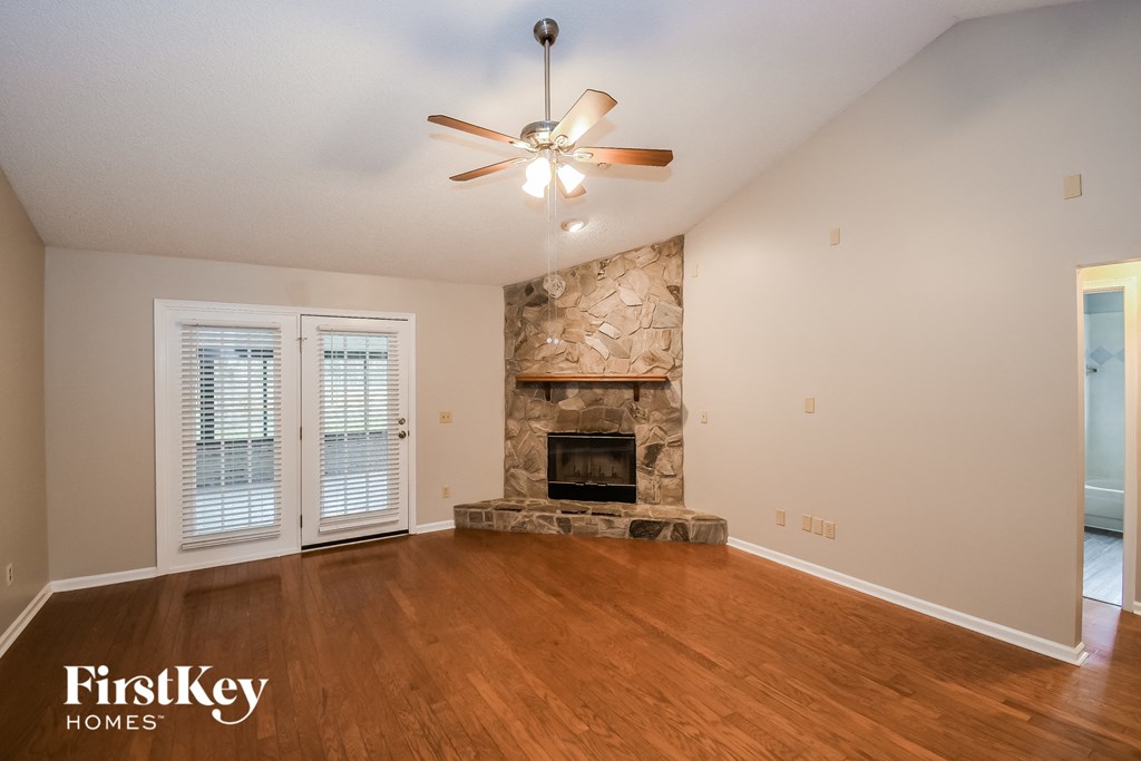 a living room with a stone fireplace and a ceiling fan