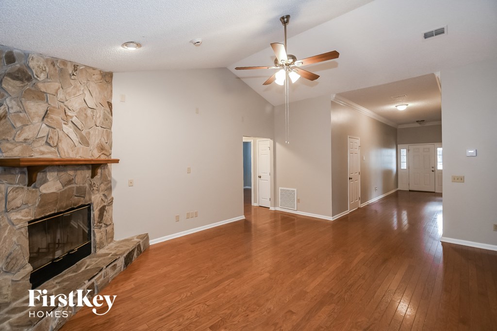 a living room with a stone fireplace and wooden floors