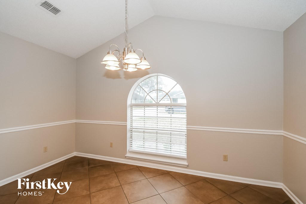 a dining room with a large arched window and tiled floors