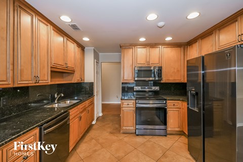 a kitchen with wood cabinets and black counter tops and black appliances