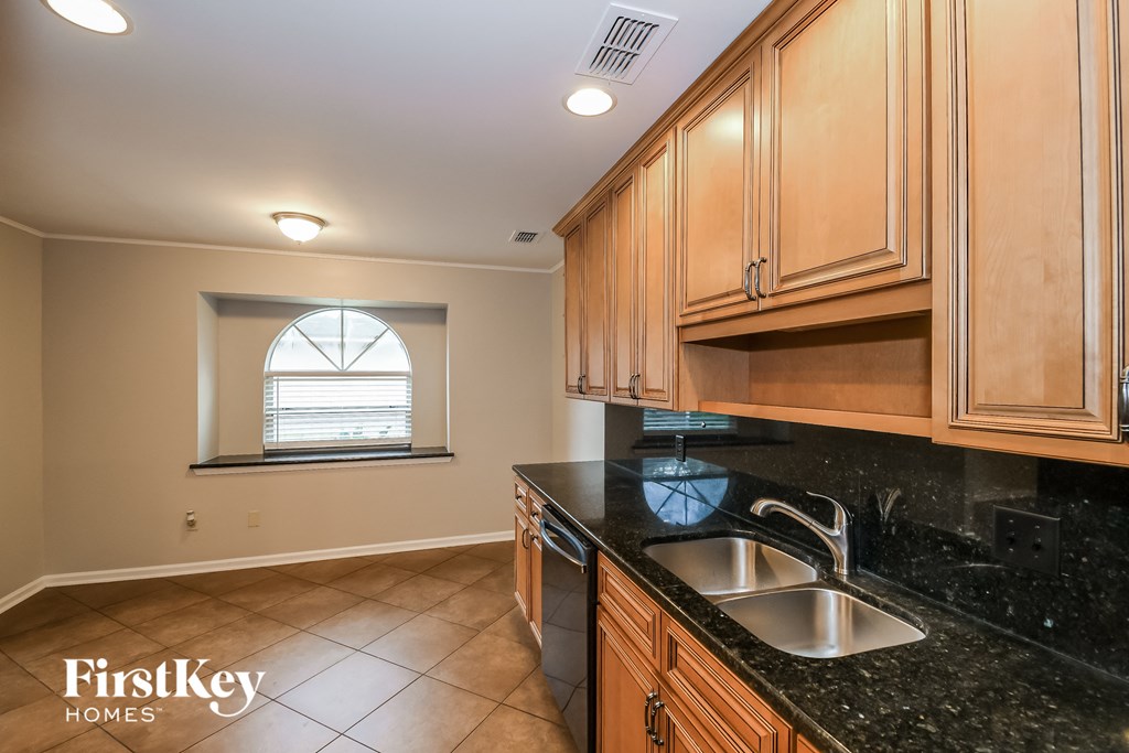 a kitchen with black granite countertops and wooden cabinets and a window
