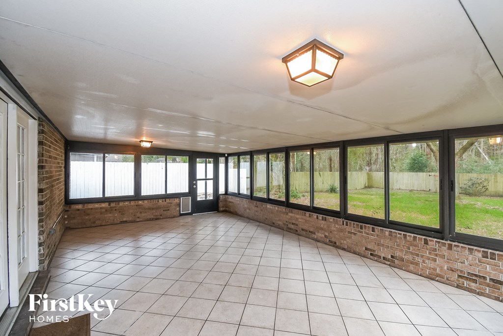 an empty living room with large windows and a tiled floor