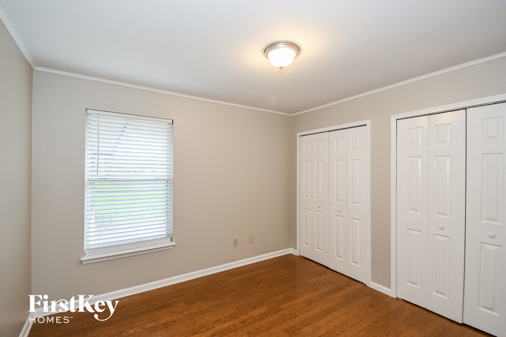 a bedroom with two closets and a window and a wood floor