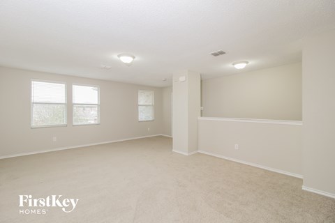 a spacious living room with beige carpet and white walls