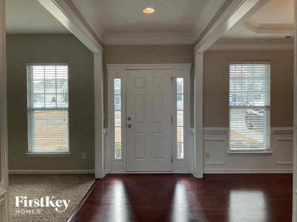 an empty living room with a white door and windows