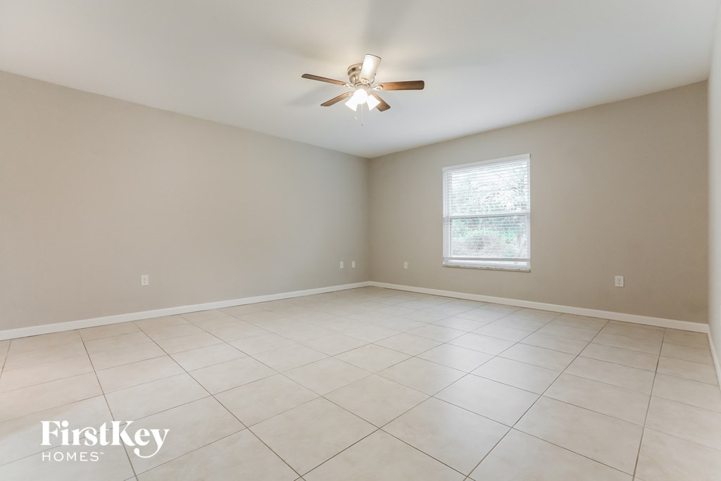 an empty living room with a ceiling fan and tiled floors