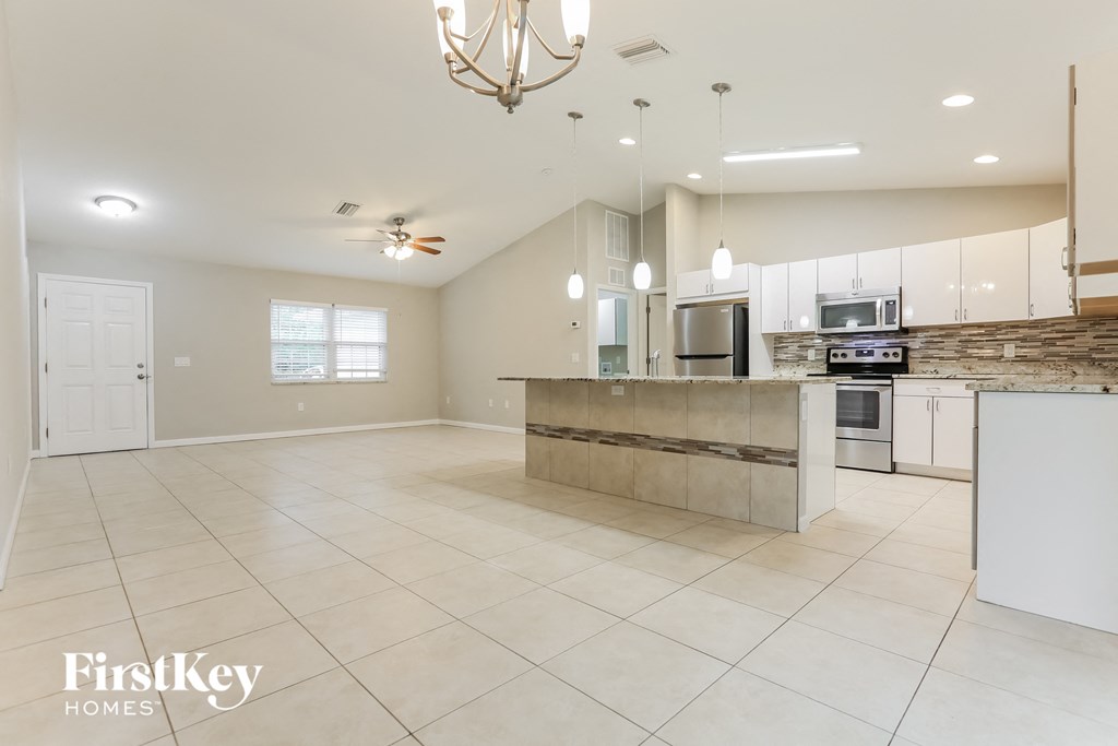 an open kitchen and living room with white tile flooring