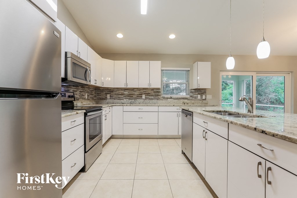 a large kitchen with white cabinets and granite counter tops