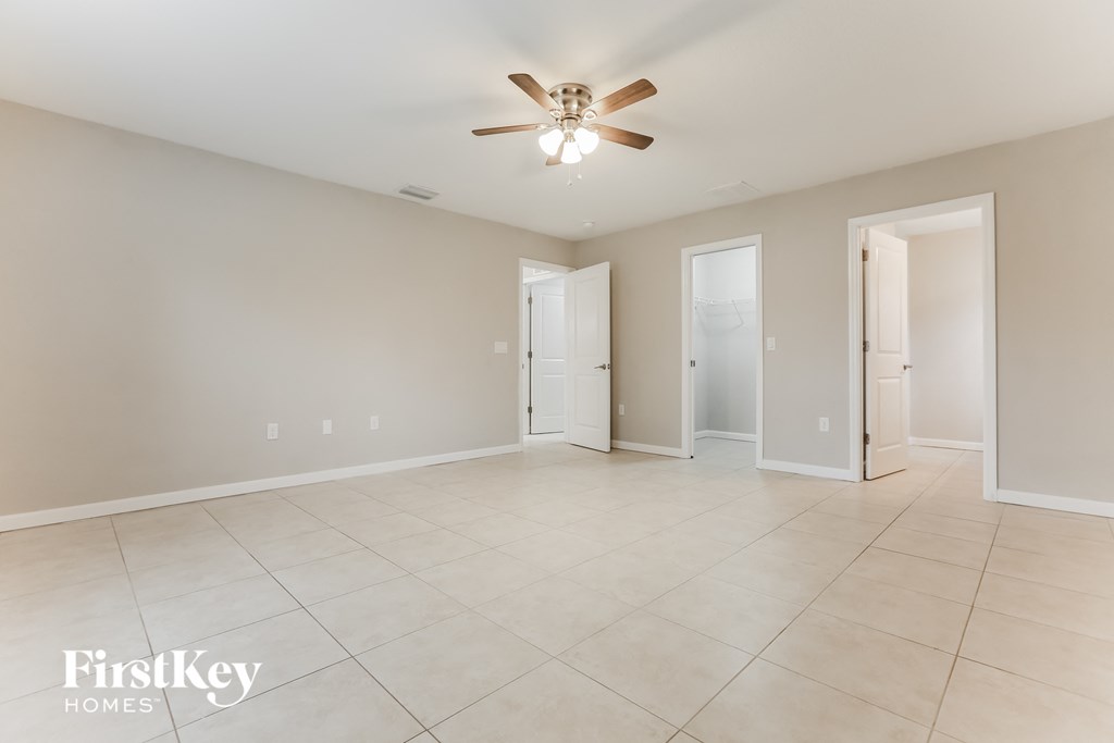 a spacious living room with tile flooring and a ceiling fan