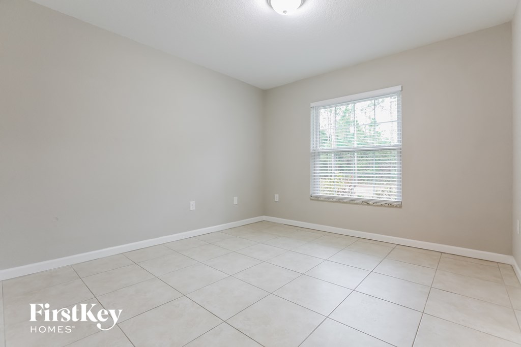 a clean and empty room with a window and tiled floors