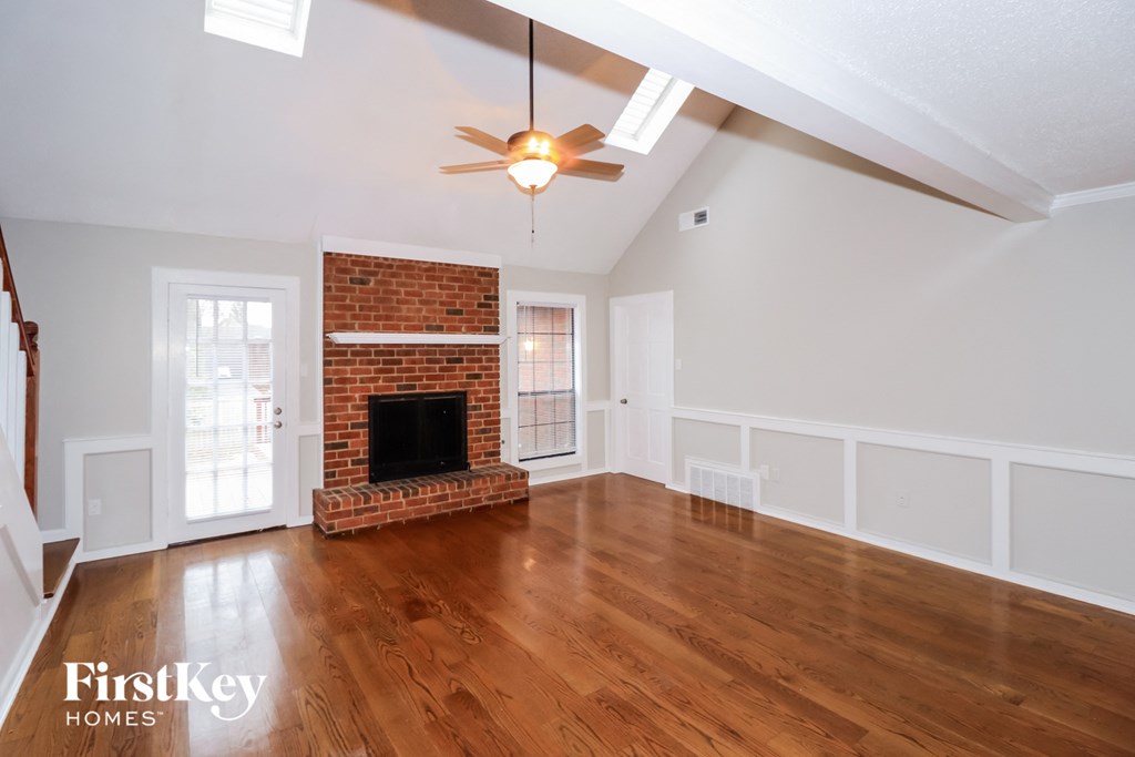 the living room of an empty house with a fireplace and a ceiling fan