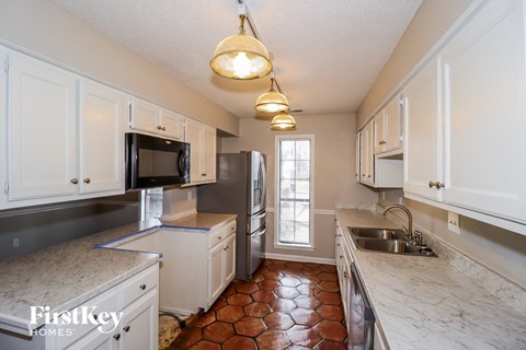 a kitchen with white cabinets and stainless steel appliances and marble counter tops