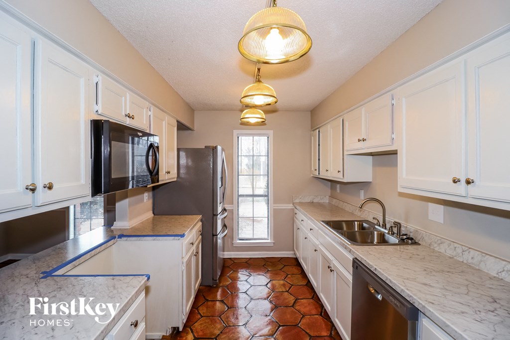 a kitchen with white cabinets and a sink and a refrigerator