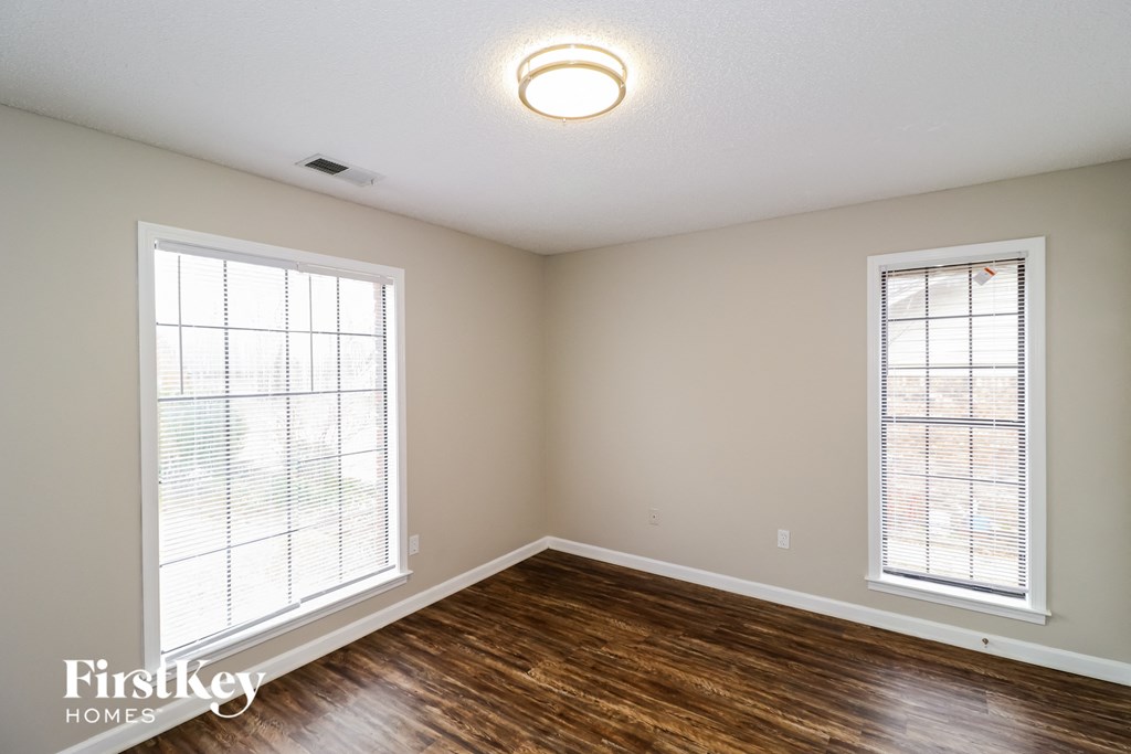 a living room with wood flooring and two windows