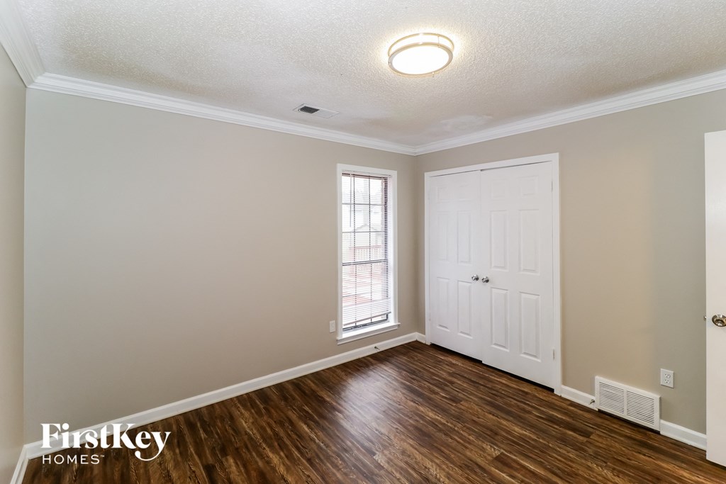 the living room of a home with a white door and wood flooring