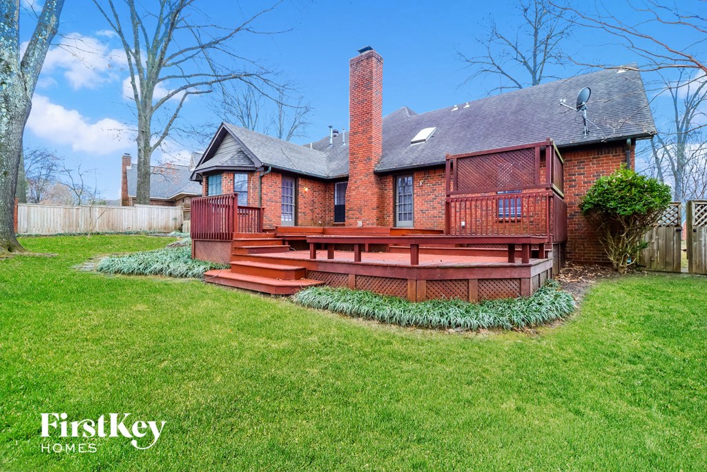 a red brick house with a wooden deck in the yard