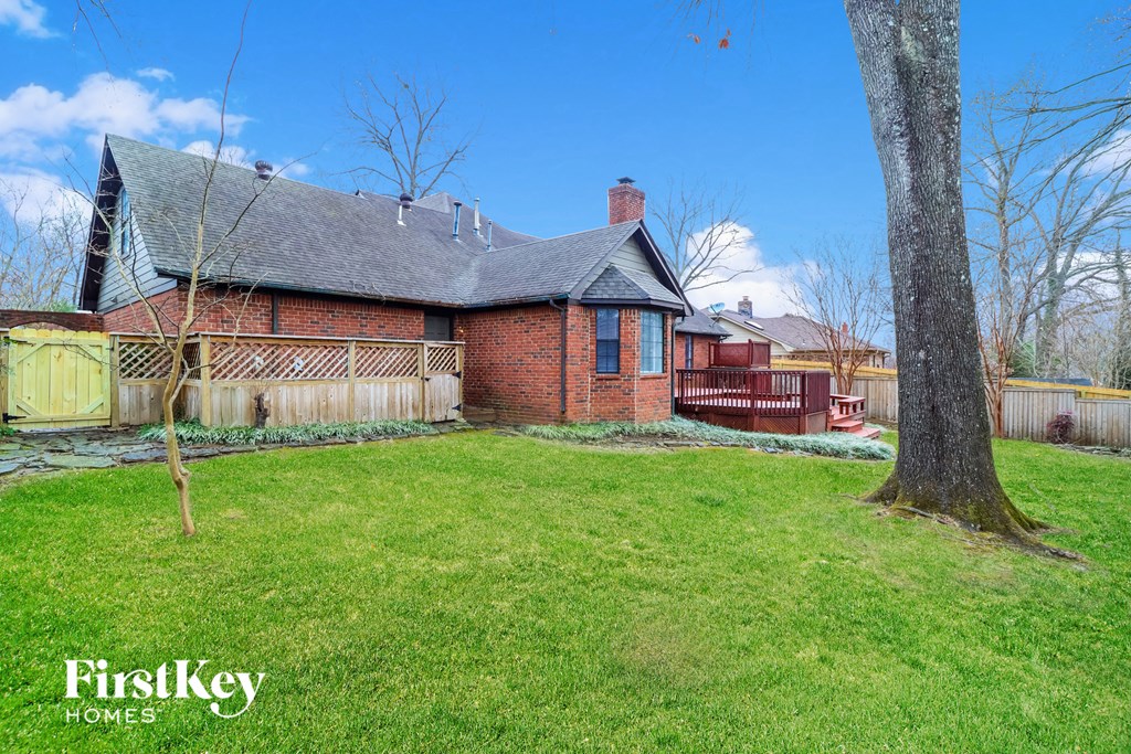 a red brick house with a yard and a wooden fence