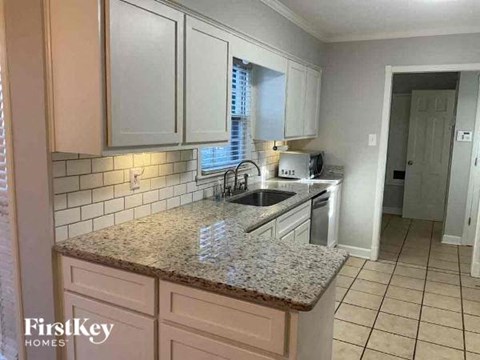 A kitchen with granite countertops and white cabinets.