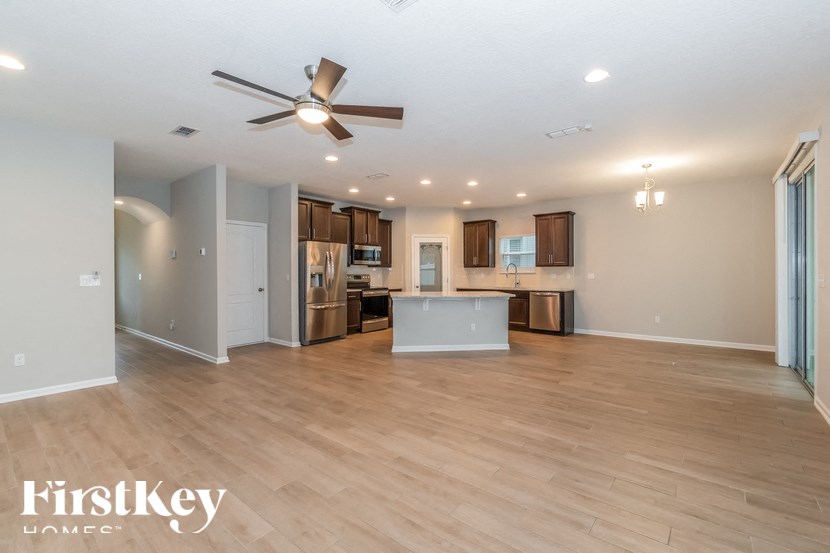 A spacious kitchen and living room with wooden floors and a ceiling fan.