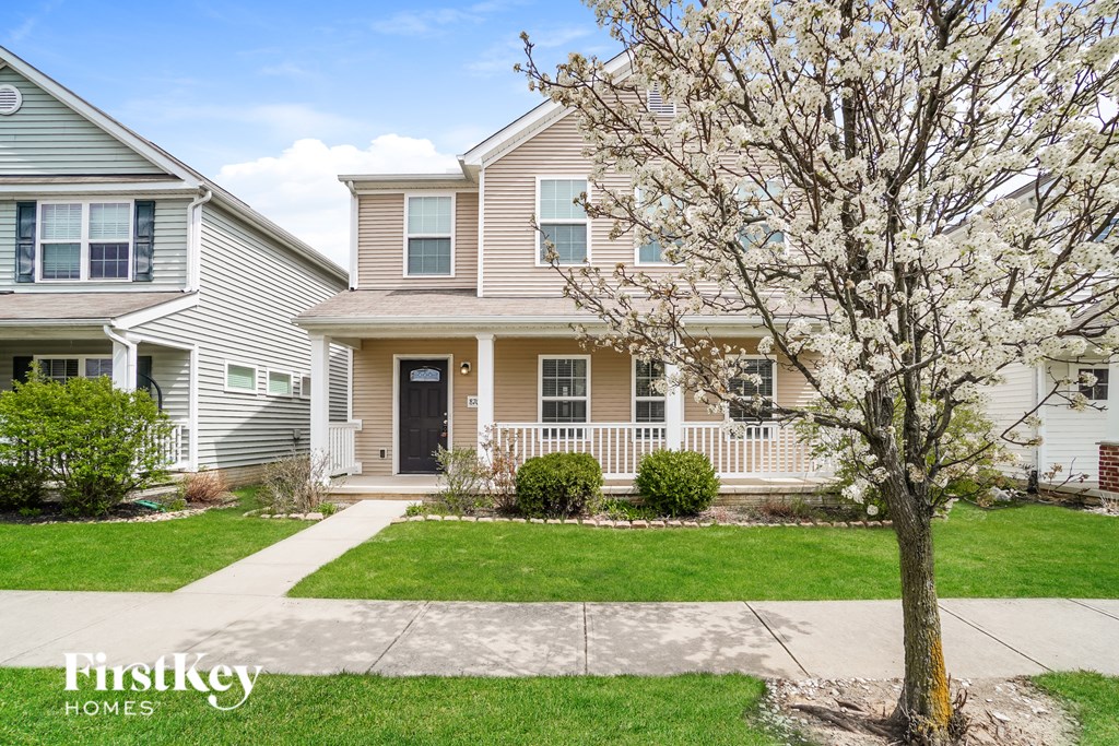 A tree with white flowers stands in front of a house.