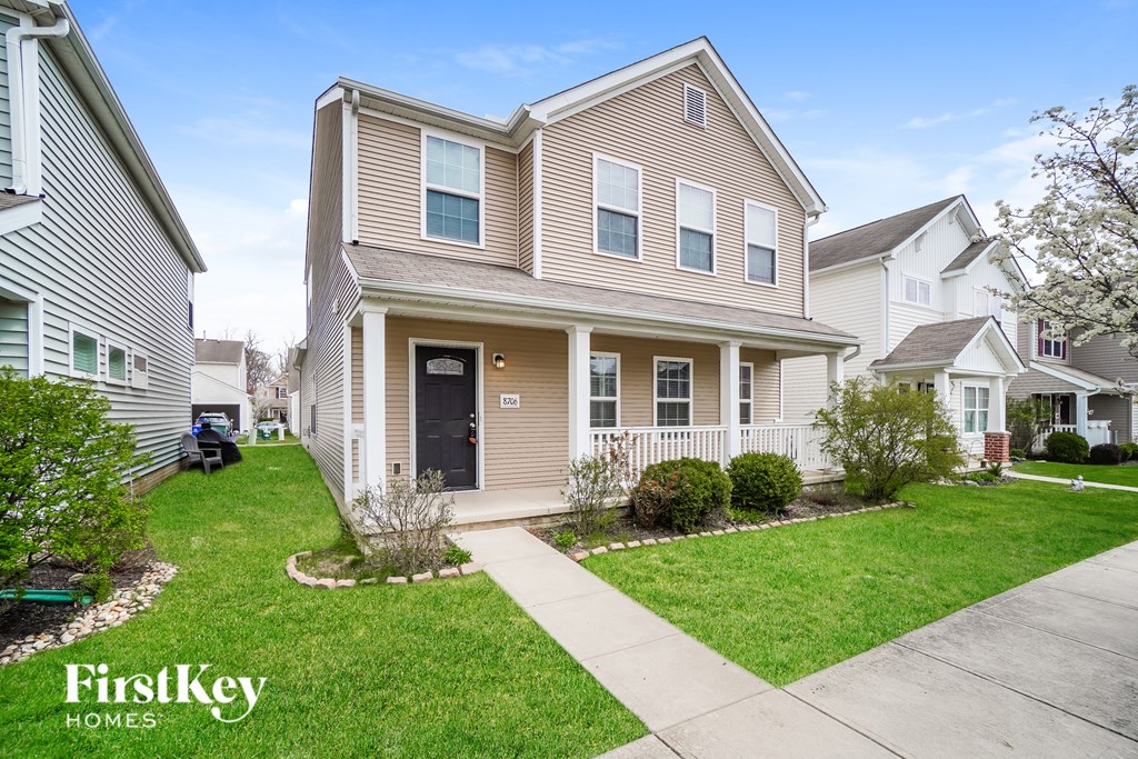 A house with a brown front door and a sign that says FirstKey Homes.