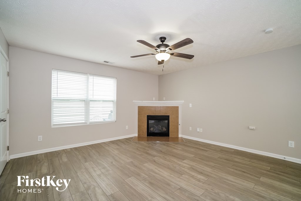 A spacious living room with a fireplace and a ceiling fan.