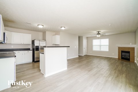 A spacious kitchen with white cabinets and a wooden floor.