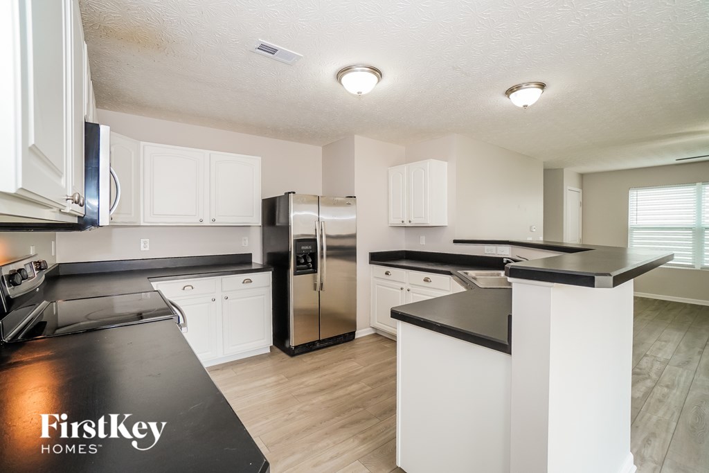 A kitchen with a black counter top and white cabinets.