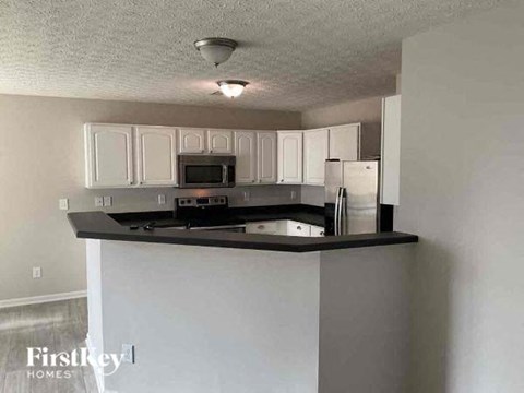 a kitchen with white cabinets and a black counter top