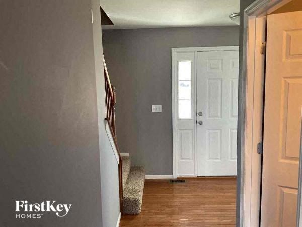 A hallway with a white door and a wooden floor.