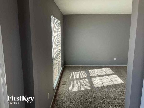 A room with a carpeted floor and a window with blinds.