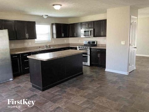 A kitchen with black cabinets and a black island.