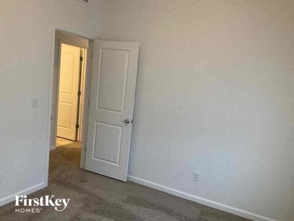 an empty room with a white door and a hallway