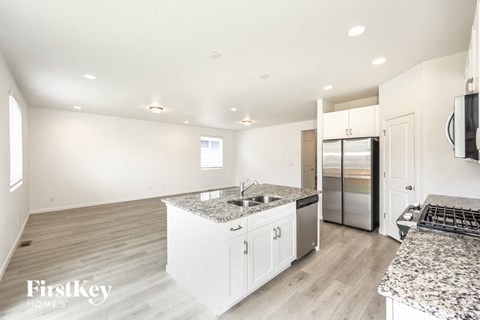 a white kitchen with granite counter tops and a stainless steel refrigerator