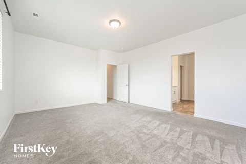 a living room with white walls and carpet and a door to a hallway