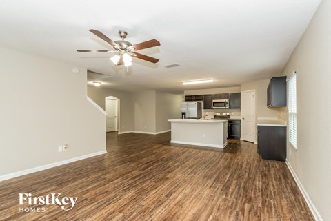 A spacious living room with wood flooring and a ceiling fan.
