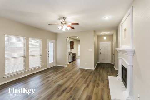 A spacious living room with wood flooring and a fireplace.