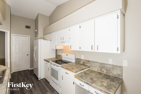 a kitchen with white cabinets and white appliances and marble counter tops