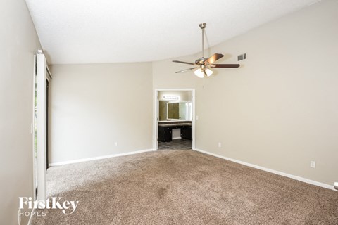 a spacious living room with carpet and a ceiling fan