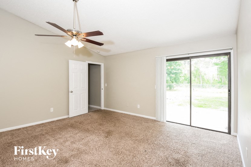 an empty living room with a ceiling fan and a door to a patio