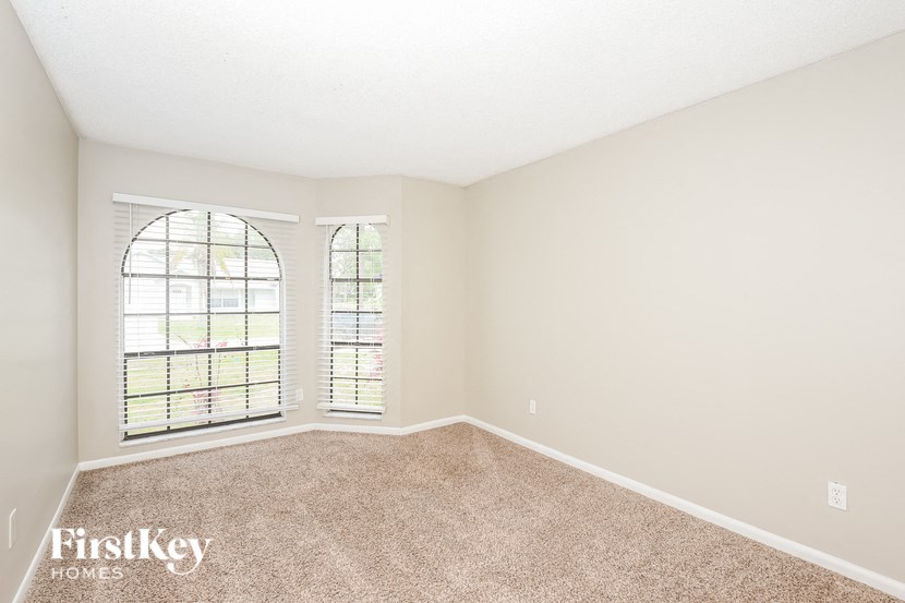 an empty living room with a large window and carpet