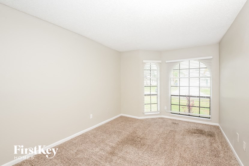 a spacious living room with carpet and a window