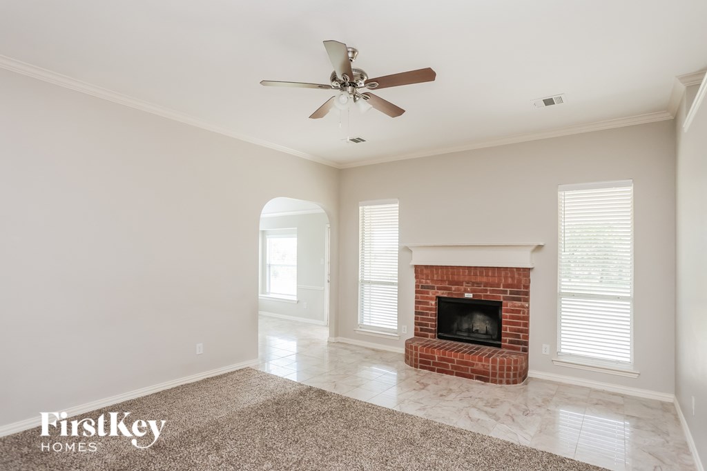 A spacious room with a fireplace and a ceiling fan.