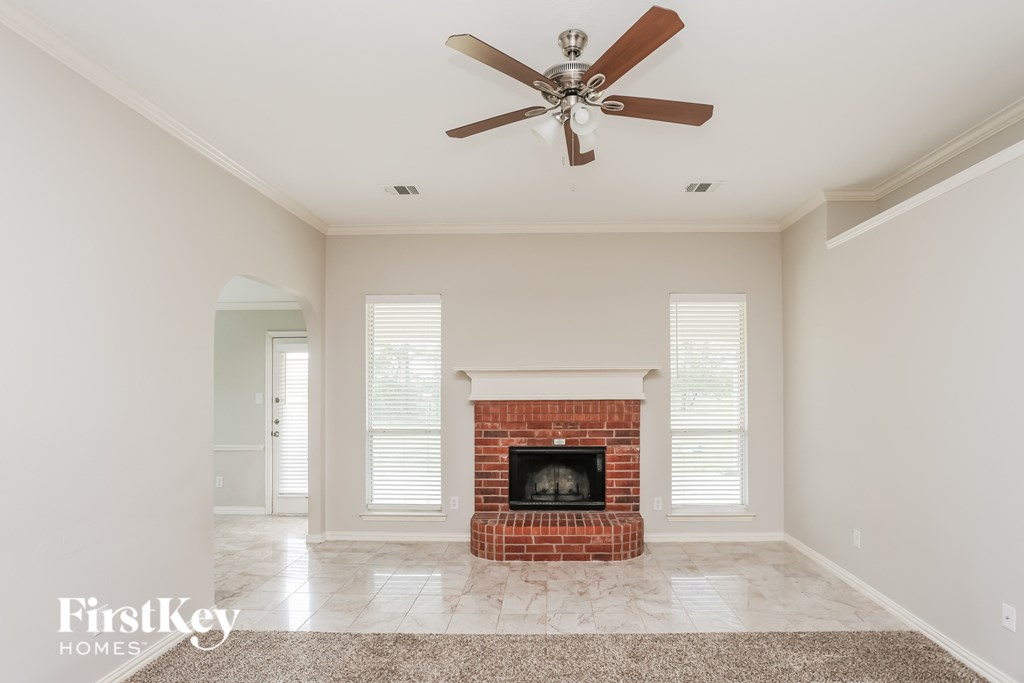 A living room with a fireplace and a ceiling fan.
