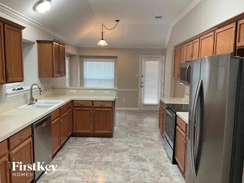 A kitchen with wooden cabinets and a marble floor.