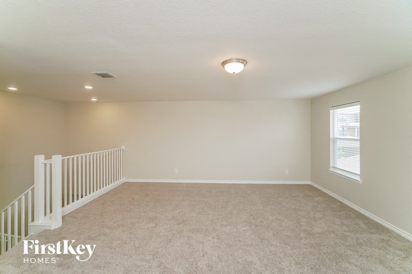 A spacious room with a carpeted floor and a window.