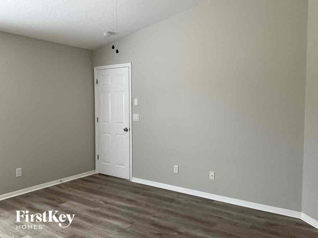 A room with a white door and wooden flooring.
